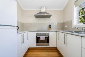 a kitchen with white cabinets and a stainless steel oven at Penfold Cottage CBD Launceston Invermay in Launceston