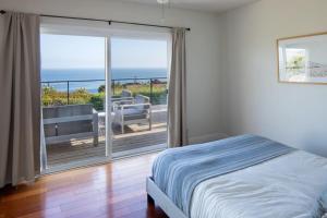 a bedroom with a bed and a balcony with the ocean at Bluff by AvantStay Gorgeous Malibu Getaway w Hot Tub Spectacular Ocean Views in Malibu