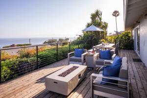 a deck with chairs and a table with a view of the ocean at Bluff by AvantStay Gorgeous Malibu Getaway w Hot Tub Spectacular Ocean Views in Malibu