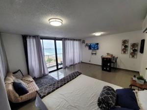 sala de estar con cama grande y ventana en Coral Beach Studio w/ Ocean View, en San Juan