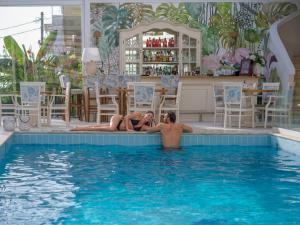 two people laying on the edge of a swimming pool at Secret Paradise Hotel & Spa in Nea Kallikrateia