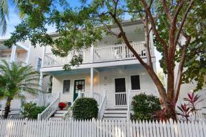 a white house with a white fence at A Little Slice Of Paradise by AvantStay Communal Pool Screened in Porch Great Location Month Long Stays in Stock Island