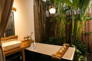 a bathroom with a large plant wall next to a bath tub at Tổ Boutique Garden in La Gi