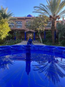 a house with a blue pool in front of it at Hotel L'Oliveraie Jnane Zitoune in Marrakech