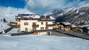 un edificio en la nieve con montañas cubiertas de nieve en Black Lake Studios - Trepalle, en Livigno