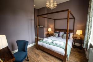 um quarto com uma cama de dossel e uma cadeira azul em The Grange em Upper Arley