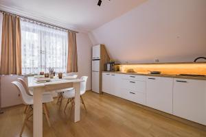 a kitchen with white cabinets and a table with chairs at Apartament u Wróbla in Leśnica