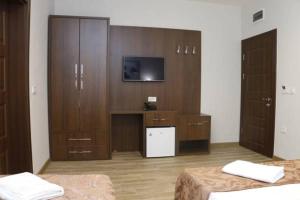 a bedroom with two beds and a tv and wooden cabinets at AEN Hotel-Old City in Skopje