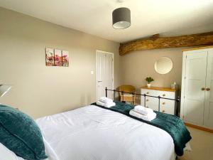 a bedroom with a white bed with towels on it at North Mere Rural Cottages in Kenilworth