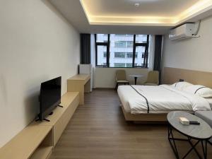 a hotel room with a bed and a flat screen tv at Weisu Service Apartment - Shenzhen Songpingshan Science and Technology Park Store in Shenzhen