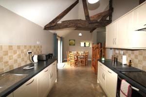 a kitchen with white cabinets and a dining room at North Mere Rural Cottages in Kenilworth