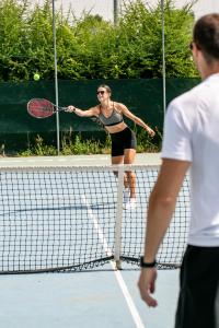 a woman hitting a tennis ball on a tennis court at Living Place Hotel in Villanova