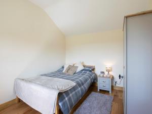 a bedroom with a bed with a blue blanket and a table at 1 Bed in Stapleton 75147 