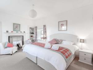 a white bedroom with a large bed and a chair at 3 Bed in Turriff 75489 in Turriff