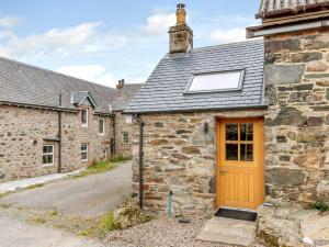 an old stone building with a orange door in front at 1 Bed in Pitlochry 75678 in Pitlochry