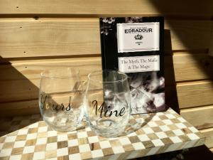 three wine glasses sitting on a table with a book at 1 Bed in Pitlochry 75678 in Pitlochry
