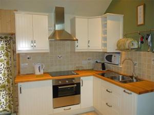 een keuken met witte kasten en een wastafel bij 1 bed in Kilmory CA344 in Kilmory