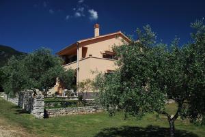 a house with a stone wall and trees in front of it at House ALEXANDRA in Nerezine in a quiet location on Losinj island in Nerezine