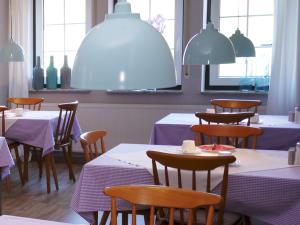 a dining room with purple tables and chairs and windows at Hus Kiek in de See in Cuxhaven