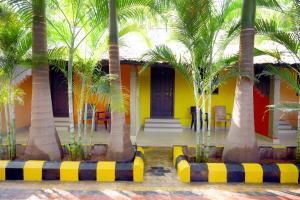 a yellow house with palm trees in front of it at Megha Resort , Hampi in Hampi