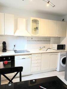 a kitchen with white cabinets and a sink and a dishwasher at Bel Appart calme proche CDG in Gonesse