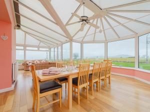 a dining room with a table and chairs and windows at 5 Bed in Mold 79345 in Llanferres