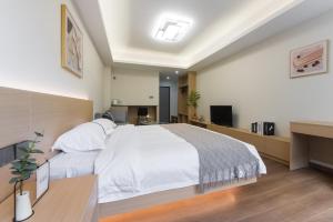 a bedroom with a large white bed and a desk at Weisu Service Apartment - Shenzhen Songpingshan Science and Technology Park Store in Shenzhen