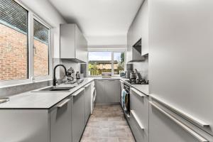 a kitchen with white cabinets and a sink and a window at Enchanting Abode in Cambridge - Pet Friendly! in Cherry Hinton