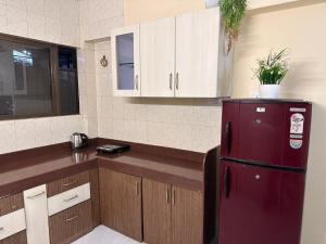 a kitchen with a red refrigerator and wooden cabinets at Jade Apartments- WiFi AC Smart Tv Kitchen in Pune