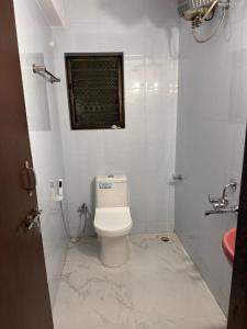 a white bathroom with a toilet and a window at Jade Apartments- WiFi AC Smart Tv Kitchen in Pune
