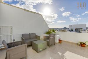 a balcony with a couch and chairs on a building at A lovely, central 2BR penthouse with large outdoor by 360 Estates in LʼInglin