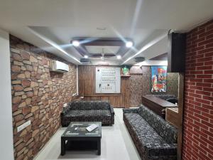 um quarto com sofás e uma parede de tijolos em Hotel Nayan palace em Kalol