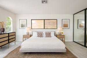 een witte slaapkamer met een bed en 2 ramen bij Archie by AvantStay Desert Retreat w Courtyard Edge of Joshua Tree in Yucca Valley