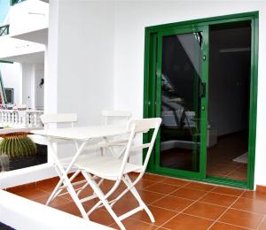 a table and chairs in a room with a green door at Playa Park 3 in Puerto del Carmen