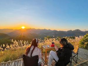 Dwie kobiety siedzące na ławce obserwujące zachód słońca w obiekcie PuBin Paradise w mieście Hòa Bình