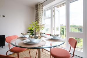 Hauzify I Cavendish flats في West Drayton: غرفة طعام مع طاولة وكراسي زجاجية