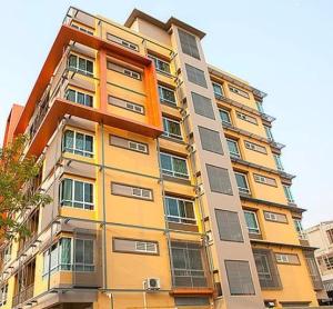 un edificio alto de color amarillo con muchas ventanas en Lasalle Park Serviced Apartment at Lasalle 75 en Bangna