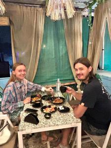 Ein Mann und eine Frau sitzen an einem Tisch mit Essen in der Unterkunft Shyam Hostel in Jodhpur