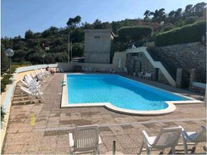una gran piscina con sillas y un edificio en Casa Ulivo con Piscina en Diano Castello