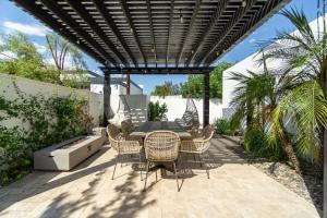 a patio with a table and chairs under a pergola at Opal by AvantStay Central Scottsdale Luxe Home in Scottsdale