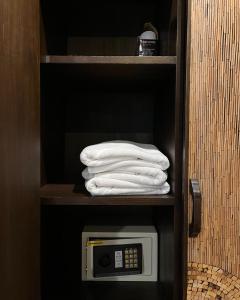 a stack of towels on a shelf with a microwave at Baan Glang Soi in Bangkok