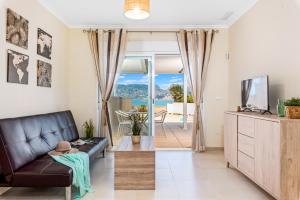 a living room with a black leather couch and a tv at Apartamento Casita Blanca - PlusHolidays in Calpe