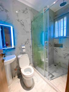 a bathroom with a toilet and a glass shower at Omah Apartments in Abuja