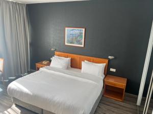 een slaapkamer met een groot bed met witte lakens bij El Sheikh Suites Hotel in Beiroet