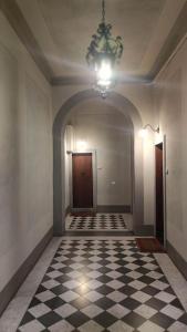 an empty hallway with a chandelier and a checkered floor at Casa nel cuore di Firenze. in Florence