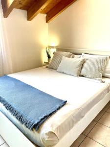 - un grand lit blanc avec une couverture bleue dans l'établissement Mansarda antica Milano, à San Giuliano Milanese