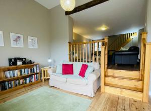 a living room with a white couch with two red pillows at North Mere Rural Cottages in Kenilworth