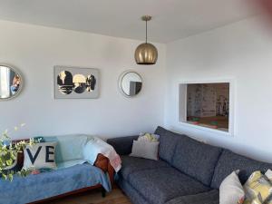 a living room with a blue couch and two mirrors at Central Sea View maisonette in Hastings