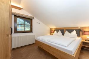 a bedroom with a bed with white sheets and a window at Haus Ennsegg by Schladming-Appartements in Haus im Ennstal