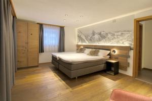 ein Schlafzimmer mit einem Bett und einem Wandgemälde in der Unterkunft Matterhorngruss Apartments in Zermatt